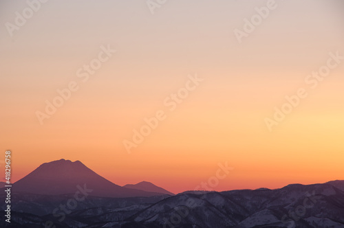 オレンジ色の夕暮れの空と山並みのシルエット。