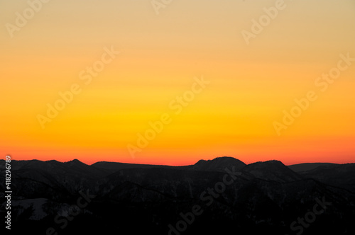 オレンジ色の夕暮れの空と山並みのシルエット。