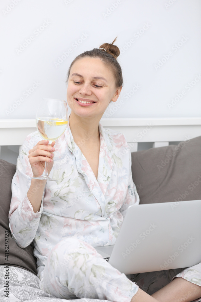glass of water with lemon in the morning for good work.smiling business woman working at home. Learns, using laptop computer and cellphone on the bed. Freelance. Writing, typing. Technology concept. glass of water with lemon in the morning for good work.smiling business woman working at home. Learns, using laptop computer and cellphone on the bed. Freelance. Writing, typing. Technology concept.