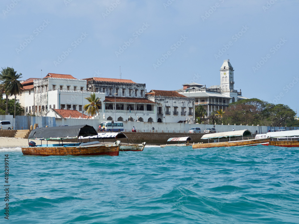 Scenic view to the Ston Town from seacoast during the day with fishing boats in the front. Stone Town, Zanzibar.