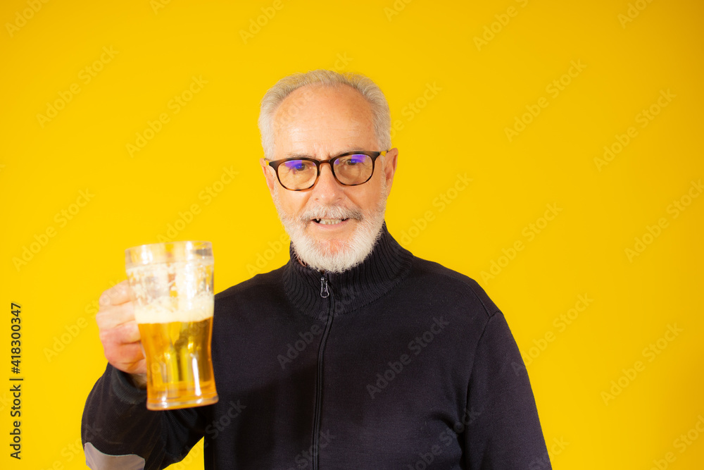 Senior handsome man drinking jar of beer standing over isolated yellow background Senior handsome man drinking jar of beer standing over isolated yellow background