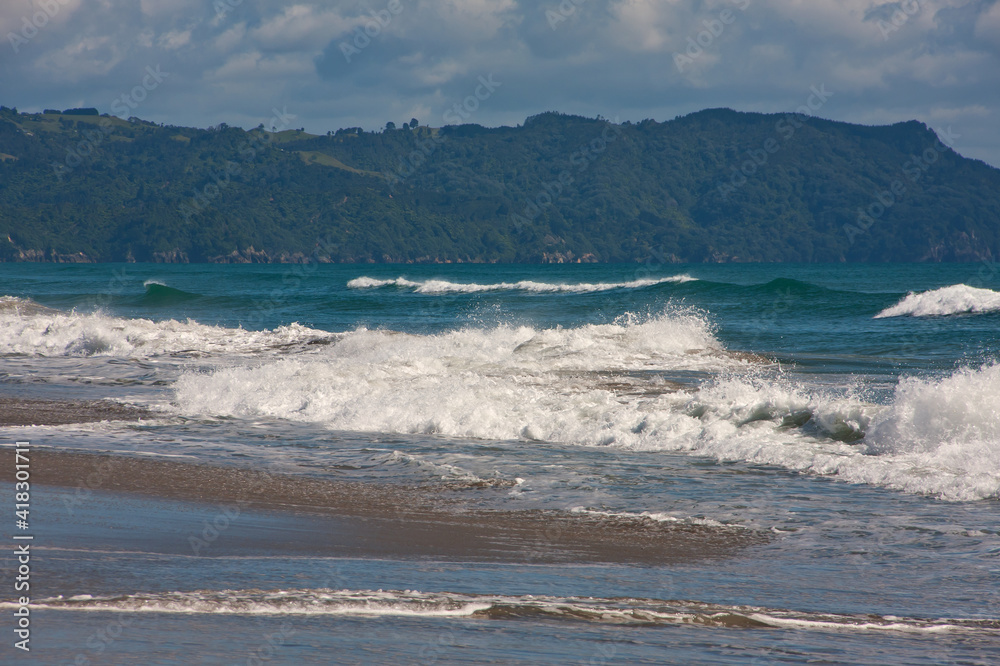 Waves on sandy beach in New Zealand