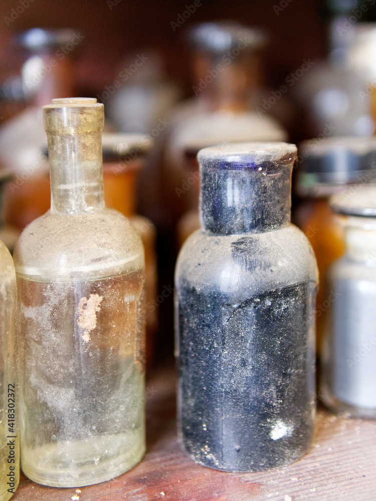 A bottle of poison on a background of old medical, chemistry and pharmacy glass. Chemistry and pharmacy history panoramic concept background. A bottle of poison on a background of old medical, chemistry and pharmacy glass. Chemistry and pharmacy history panoramic concept background.