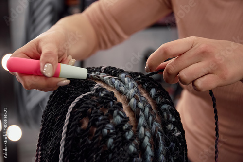 The hairdresser braids the girl in afro-braids in the beauty salon. Close-up