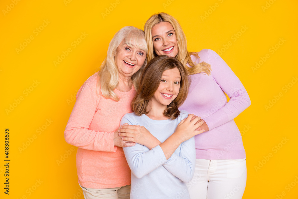 Photo of nice optimistic three woman grand mom daughter hug wear pastel cloth isolated on yellow color background Photo of nice optimistic three woman grand mom daughter hug wear pastel cloth isolated on yellow color background