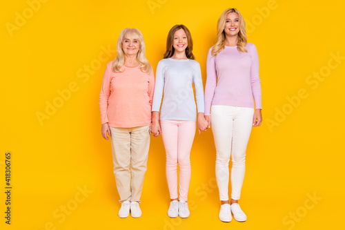 Full size photo of nice optimistic three woman grand mom daughter stand wear pastel cloth isolated on yellow color background