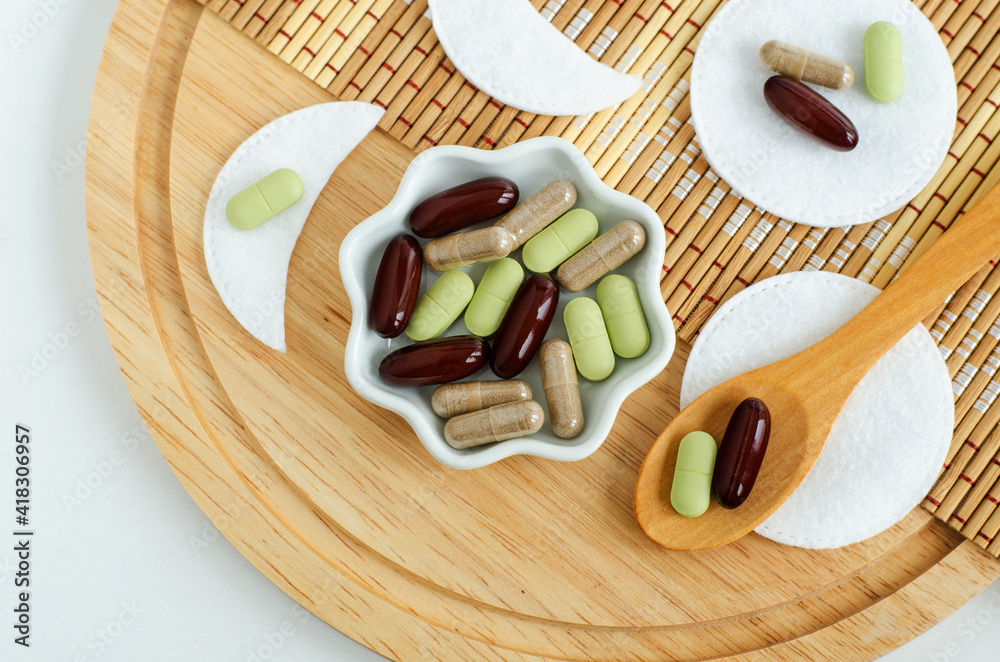 Small white bowl with food supplement capsules, pills and cotton pads. Natural healthcare, skin care and beauty treatment. Top view, copy space. Small white bowl with food supplement capsules, pills and cotton pads. Natural healthcare, skin care and beauty treatment. Top view, copy space.