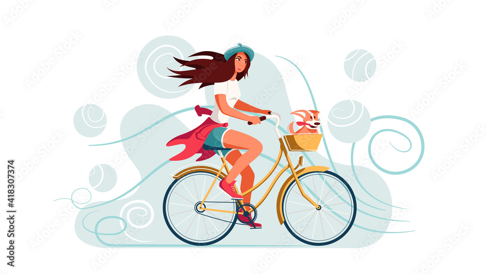Fototapeta premium A young woman rides a bicycle with a dog in a basket.