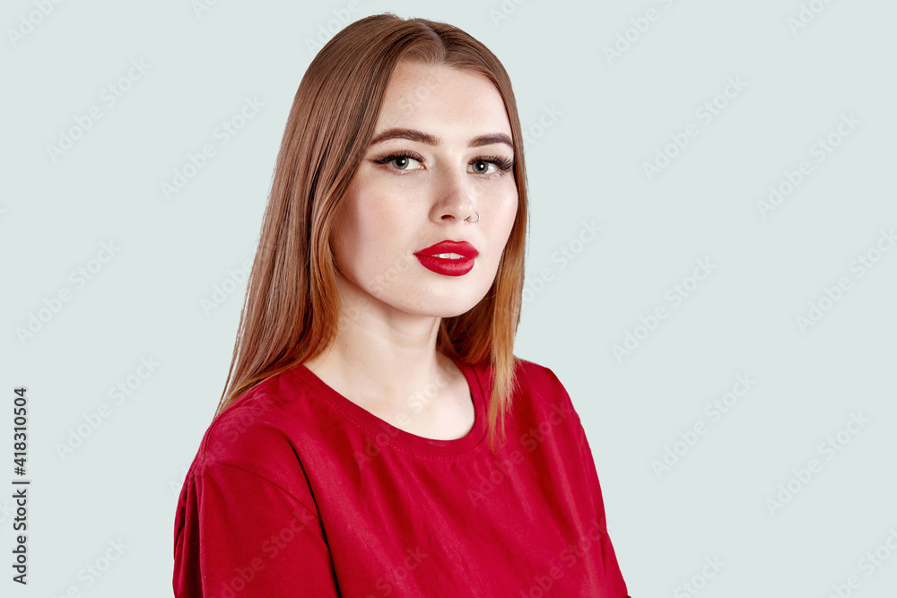 Beautiful face of young adult woman with nose earring and clean fresh skin. Portrait of cute brunette with red lips and nose piercing posing in a red t-shirt on gray Beautiful face of young adult woman with nose earring and clean fresh skin. Portrait of cute brunette with red lips and nose piercing posing in a red t-shirt on gray