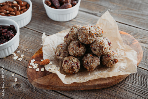 Close-up of homemade dried fruit, nuts and oatmeal balls. Energy bols on a wooden board and ingredients nearby. Vegetarian, vegan raw dessert photo