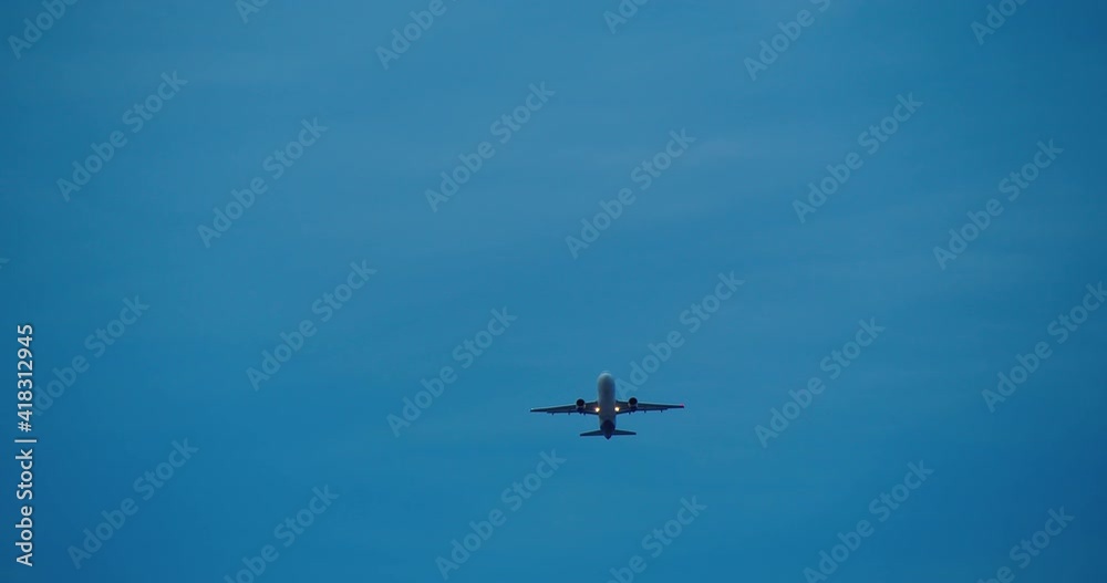 The plane is flying through the evening blue sky. The plane is flying through the evening blue sky.