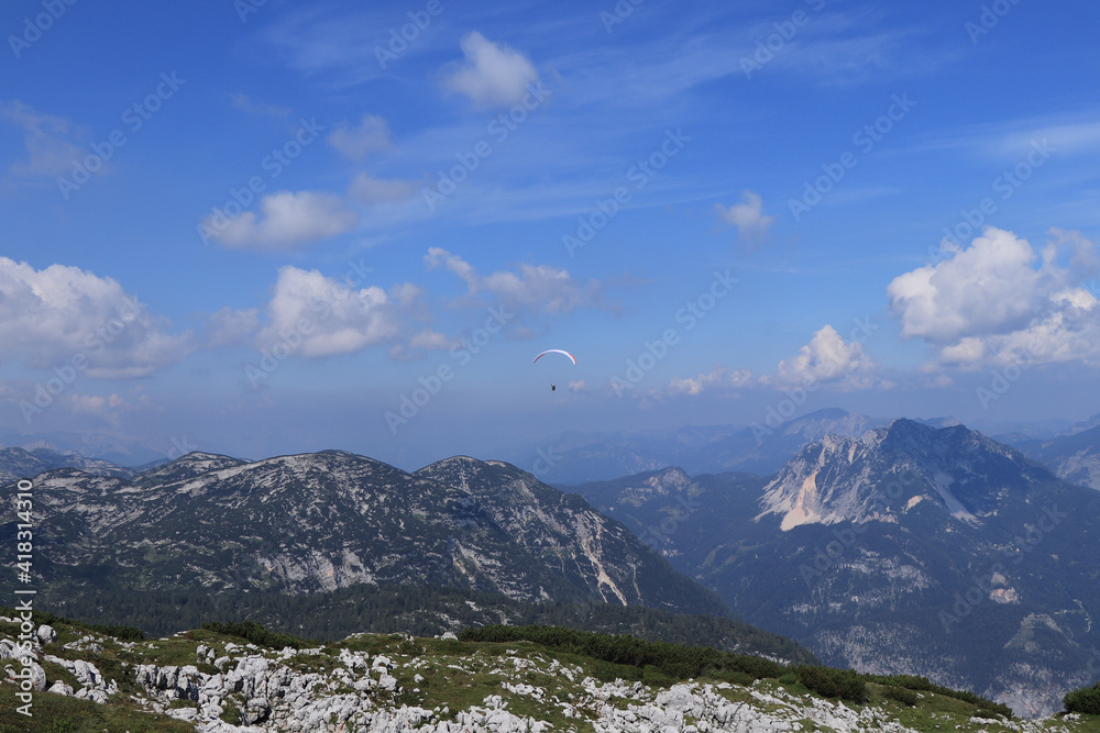 experienced parachutist flies in the right wind and drives a parachute around the Austrian Alps. Paratrooper with a white-blue parachute made of a special fiber. Dangerous sport. Around krippenstein