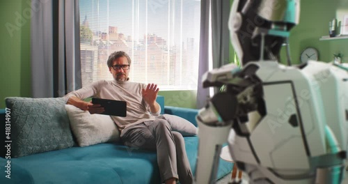 Mature man turning off android robot at home