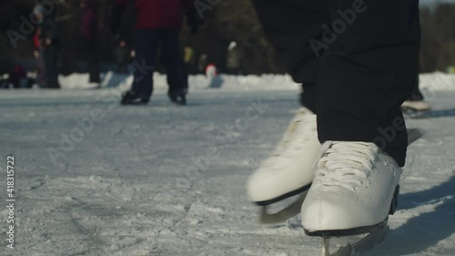 Detail view of a Woman's white Ice skating shoes skating on a frozen lake in Lhotka, Kokorin, Czech Republic - Ground level static close up detail shot photo