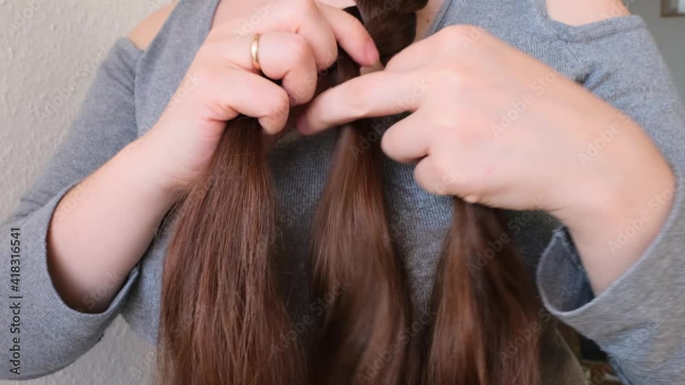 young woman, brunette, braids her long beautiful hair in a thick braid, concept of hygiene, hair care, traditions young woman, brunette, braids her long beautiful hair in a thick braid, concept of hygiene, hair care, traditions