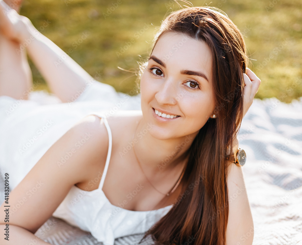 Girl in the spring in the park. Brunette with long hair lies on a plaid on a background of summer nature. Youth and beauty. Girl in the spring in the park. Brunette with long hair lies on a plaid on a background of summer nature. Youth and beauty.