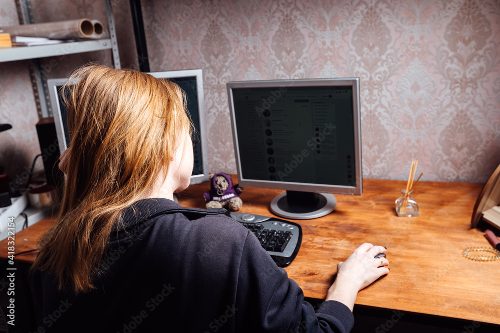 a girl is typing on a keyboard, working at a personal computer from home, a man is sitting in front of two monitors