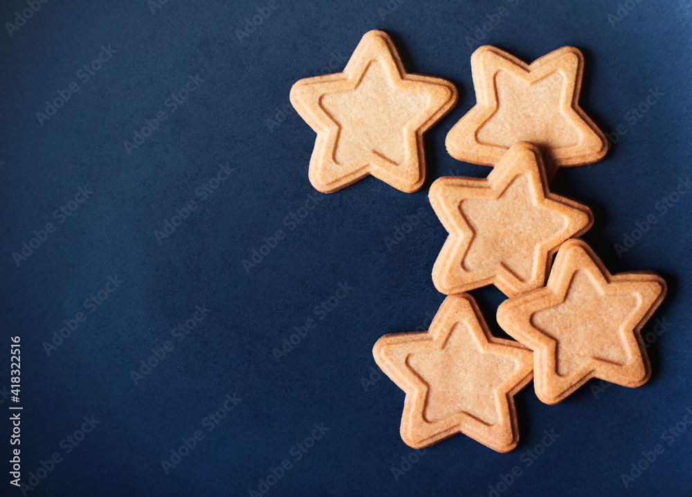 A beautiful delicious cookie in the shape of stars lies on a blue background, depicting the night starry sky. Holiday food. A beautiful delicious cookie in the shape of stars lies on a blue background, depicting the night starry sky. Holiday food.
