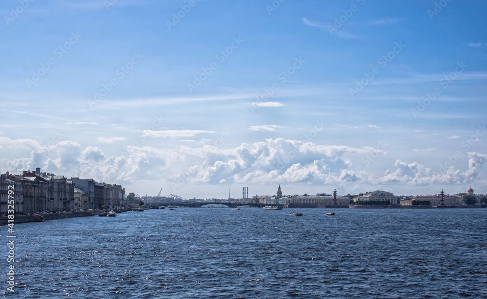 Beautiful urban river landscape. Big river with boats and blue cloudy sky. Embankment with old historical buildings and a bridge on the background