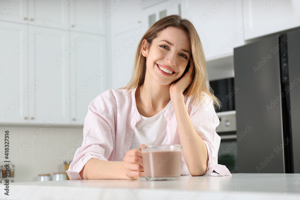 Young woman with glass cup of chocolate milk in kitchen Young woman with glass cup of chocolate milk in kitchen