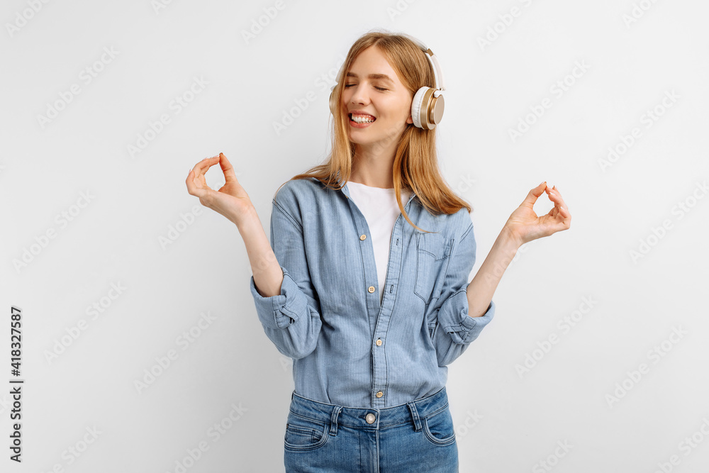Obraz premium Cheerful young woman listening to music on headphones over white background