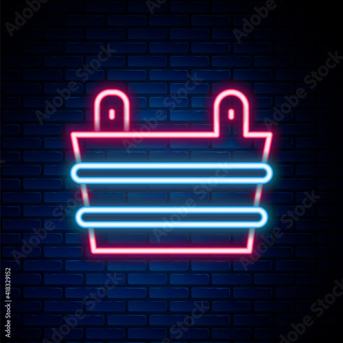 Glowing neon line Sauna bucket icon isolated on brick wall background. Colorful outline concept. Vector.