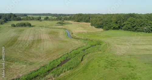 Aerial view, slowly ascending, of small winding river between grasslands, river Reest, border between provinces of Drenthe and Overijssel, Netherlands photo
