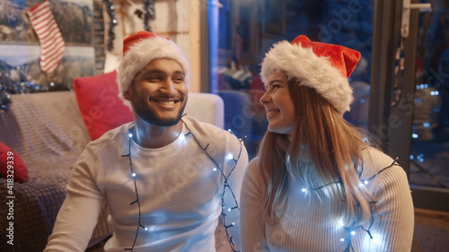 Happy young couple with santa hats smiling to each other and flirting. High quality photo