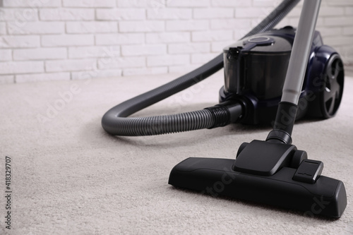 Modern vacuum cleaner on carpet indoors, closeup. Space for text