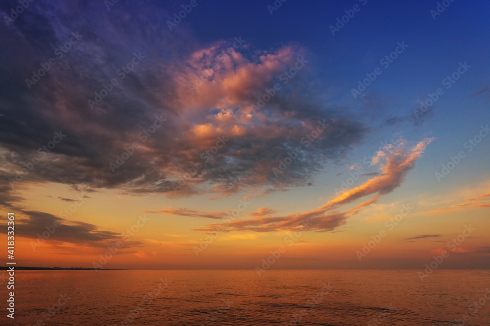 Beautiful sunset, dawn, over the sea, ocean, against the background of the blue sky and colorful clouds
