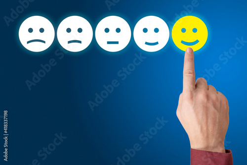 Human hand is rating with happy icon. Ranking and customer satisfaction concept. Excellent Customer Service Evaluation. copy space. blue background
