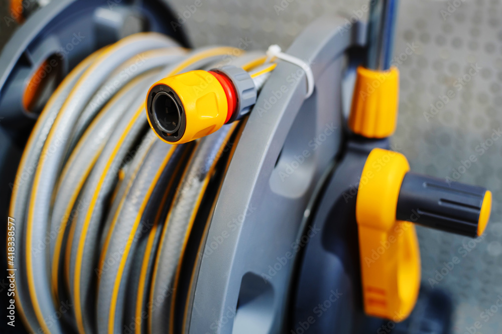 Garden hose on a large plastic reel. Equipment for watering plants and household needs. Close-up Garden hose on a large plastic reel. Equipment for watering plants and household needs. Close-up