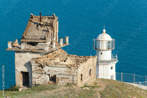 Lighthouse at Cape Meganom on a sunny day. The ruined house of the lighthouse keeper. photo