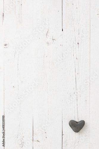 Stone heart decoration on an aged wooden table. Background for postcards with space for text. Festive season. Heart of natural stone in the corner of the frame