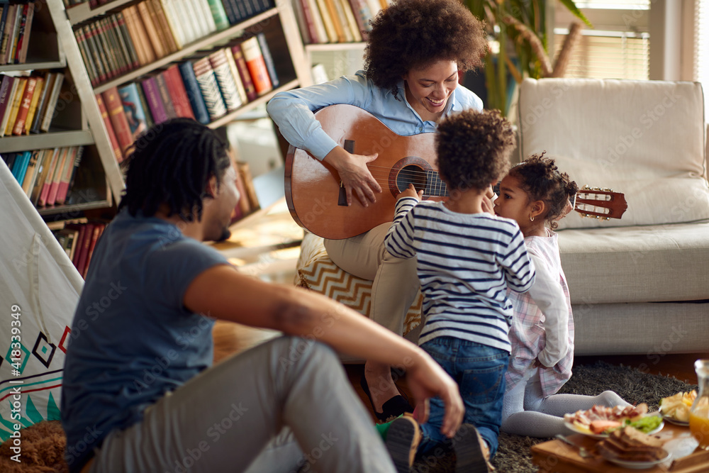 Kids are interested in the guitar played by their Mom at home. Family, together, love, playtime Kids are interested in the guitar played by their Mom at home. Family, together, love, playtime