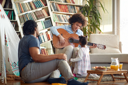 Happy family enjoying the sound of the guitar at home. Family, together, love, playtime