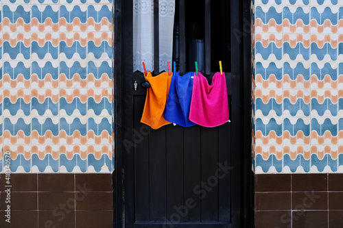 towels in a row on clothesline admist portuguese azulejos on wall