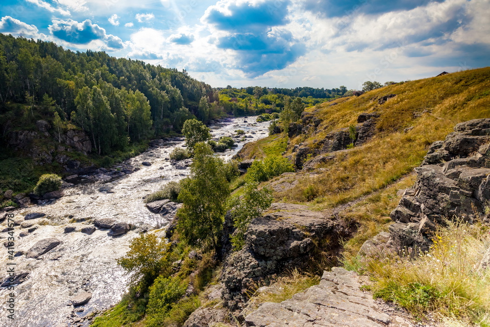 Fast river with rocky banks, overgrown with trees in summer Fast river with rocky banks, overgrown with trees in summer