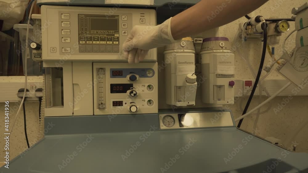 Anaesthetist doctor changing setting in anaesthetic machine work station for patient with coronavirus in hospital