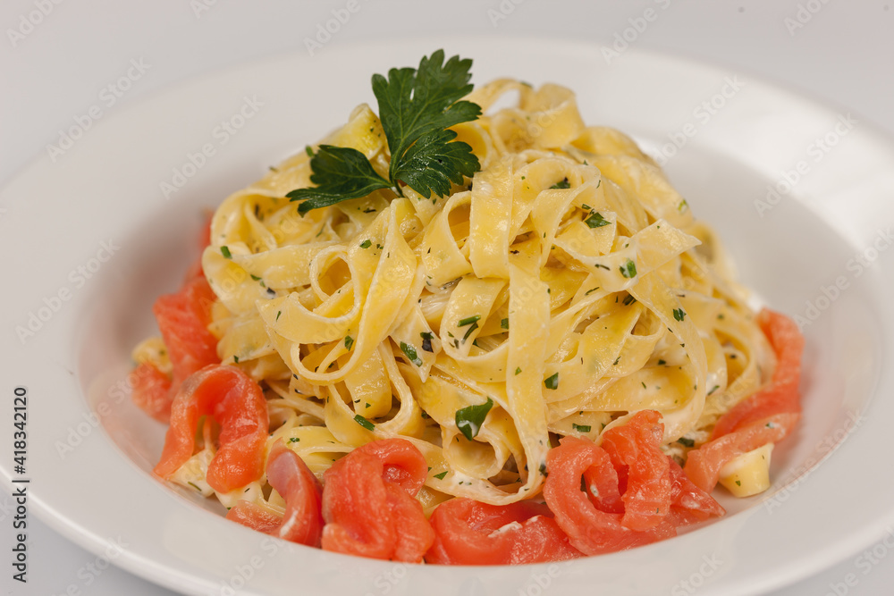 Fettuccine pasta with salmon on a white background
