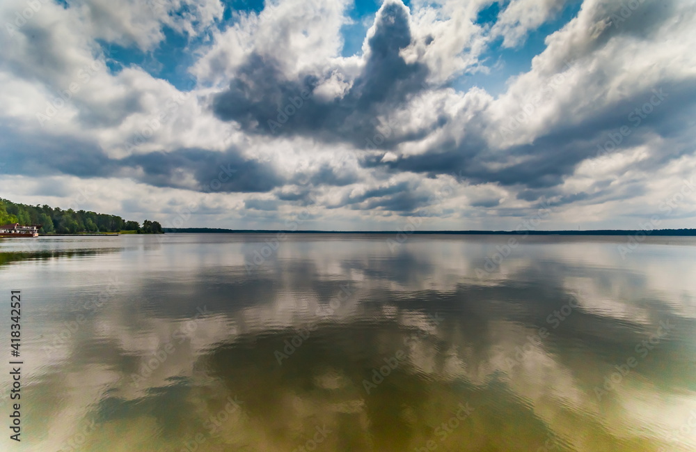 Fototapeta premium River banks against blue sky with white clouds in summer