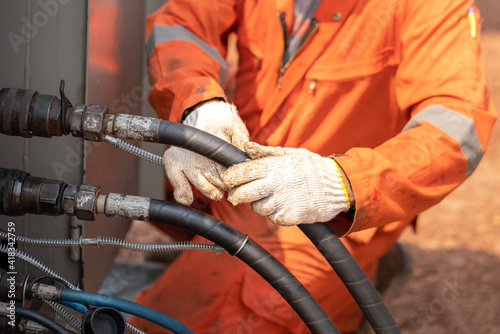 Action of worker hand is connecting and checking to high-pressure hydraulic hose line of  power pack engine. Industrial working action photo, Close-up and selective focus. 