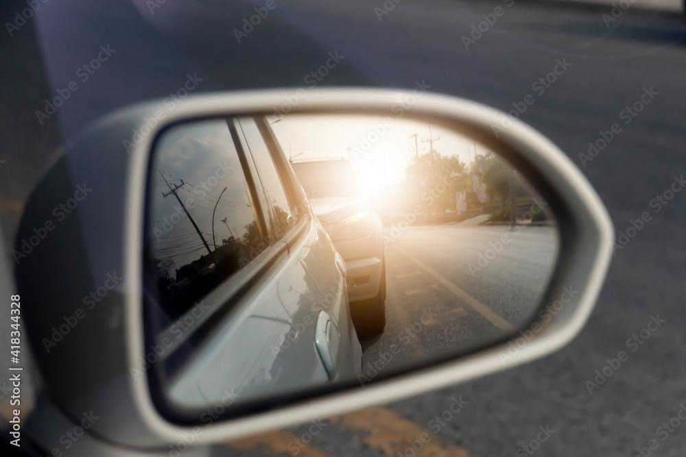 Abstract and blurred of view mirror side of white car with other cars that are parked at the end of the queue and turn on the lights With an orange light shining. Abstract and blurred of view mirror side of white car with other cars that are parked at the end of the queue and turn on the lights With an orange light shining.