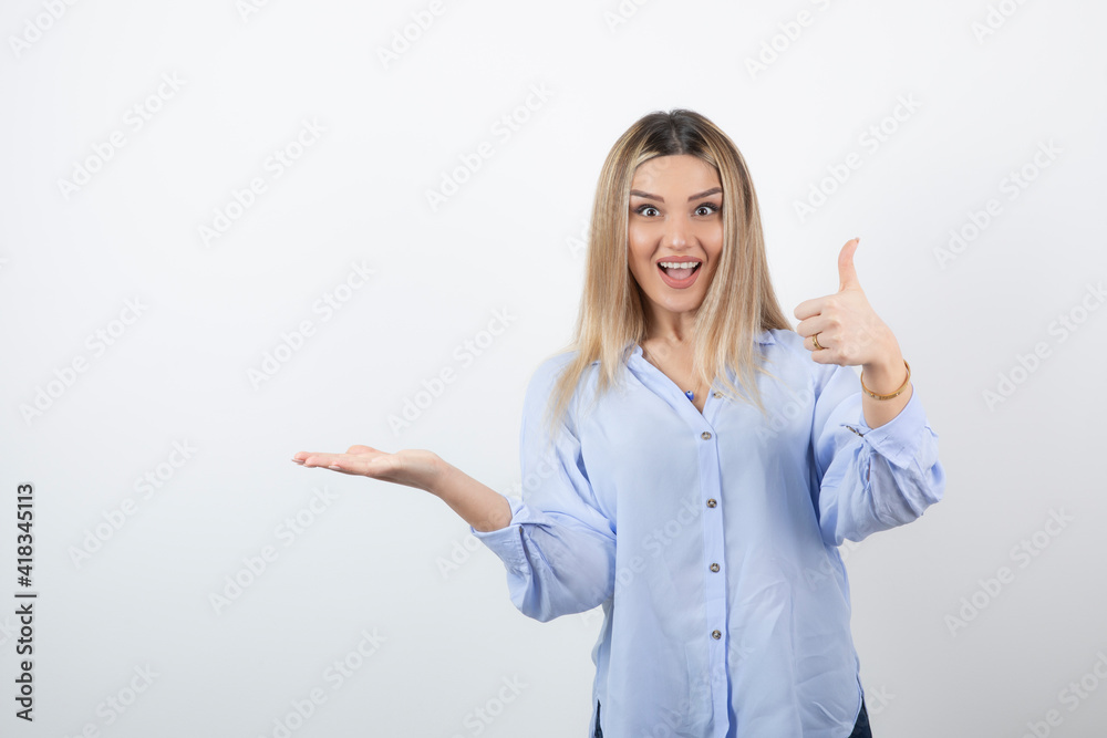 Image of young pretty woman standing and giving thumbs up on white background Image of young pretty woman standing and giving thumbs up on white background