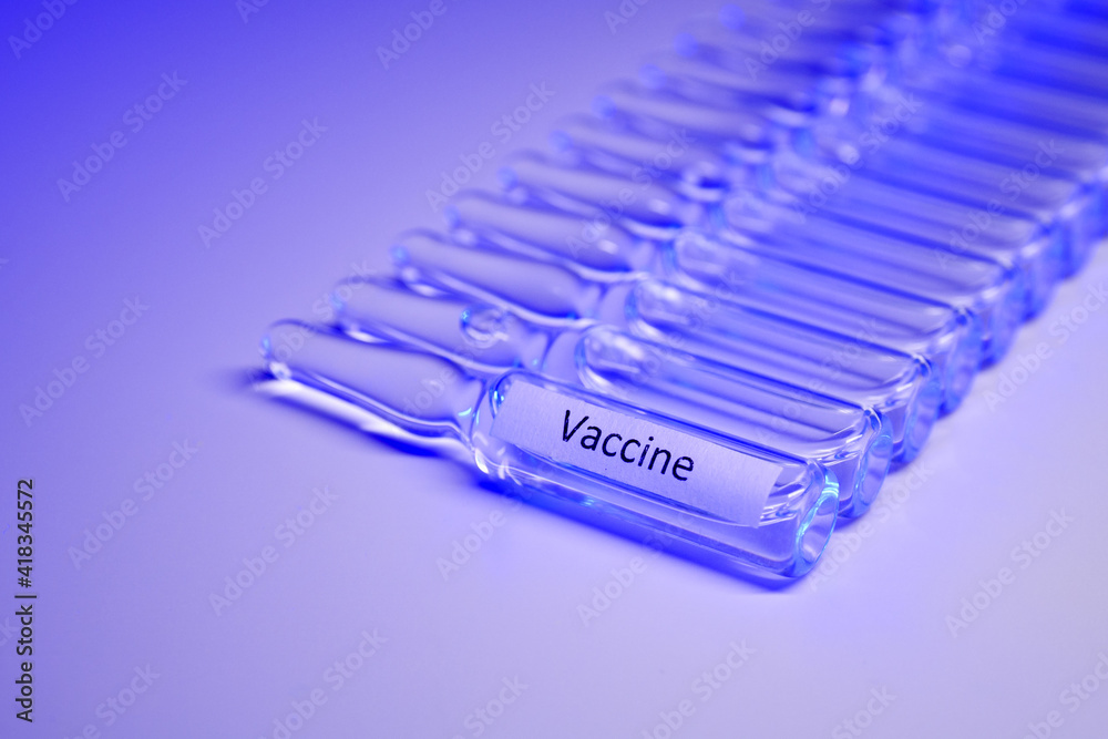 Glass ampoules with a clear liquid are laid out in a row on the table. Vaccine in ampoule for injection. Coronavirus vaccine Glass ampoules with a clear liquid are laid out in a row on the table. Vaccine in ampoule for injection. Coronavirus vaccine