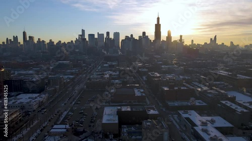 aerial drone establishing shot footage of Chicago downtown area during the winter time early in the morning after sunrise.  the white snow covers most of the city architecture landscape.   