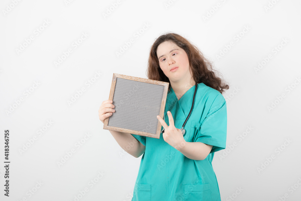 Image of a young girl in green uniform with a frame showing victory sign Image of a young girl in green uniform with a frame showing victory sign