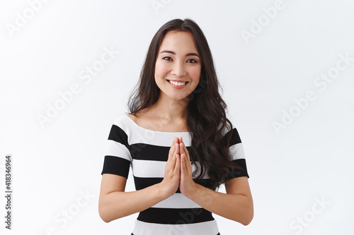 Fototapeta Charming nice east-asian female in striped t-shirt hold hands in pray, palms cla