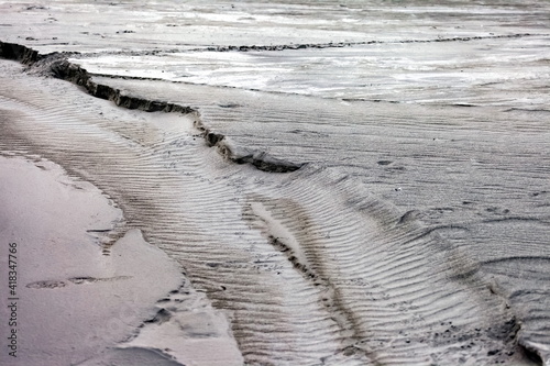 Traces of running water on the gray sand. Background