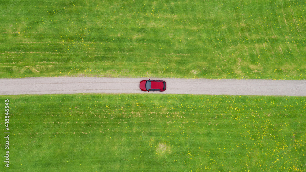 Obraz premium Aerial view looking down on a rural road in the Finland countryside with a car racing along it.